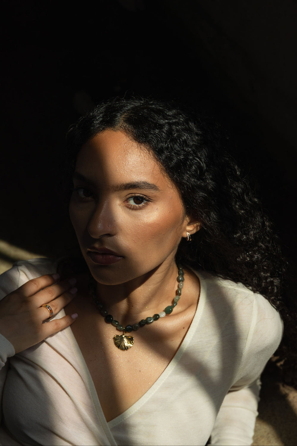 Woman wearing a necklace of a gold shell with a dark background