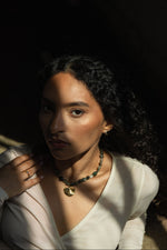 Woman wearing a necklace of a gold shell with a dark background